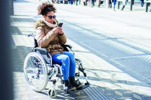 Woman in a wheelchair waiting for the bus.